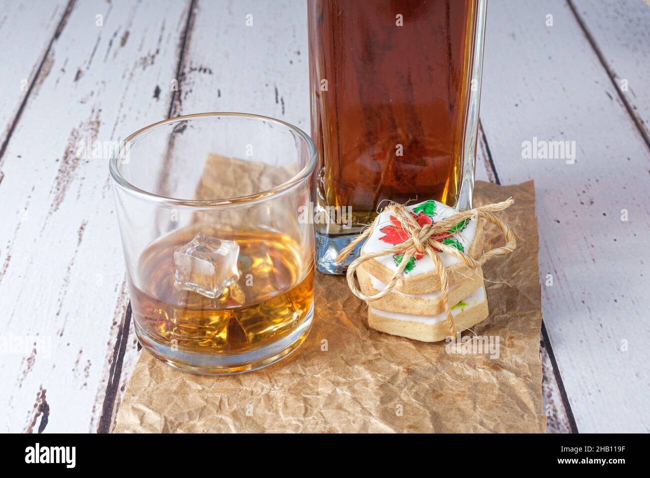 Glass of whiskey with ice on brown paper next to buttery cookies. Stock Photo