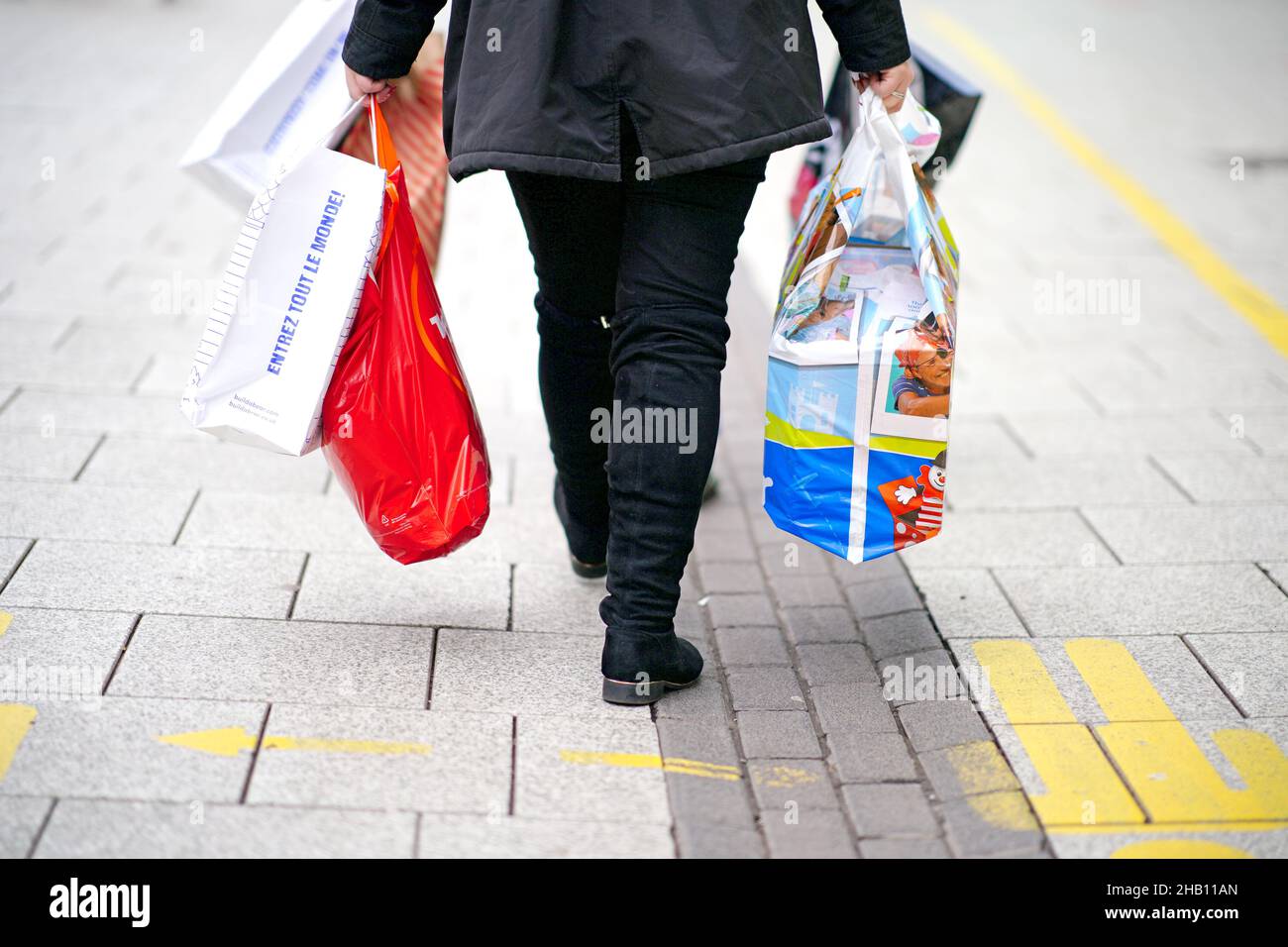 Christmas shoppers carry bags through the centre of Cardiff, Wales, where people have been told to prepare for more restrictions in the coming weeks as the country faces an impending 'tsunami' from the Omicron variant of Covid-19. Picture date: Thursday December 16, 2021. Stock Photo