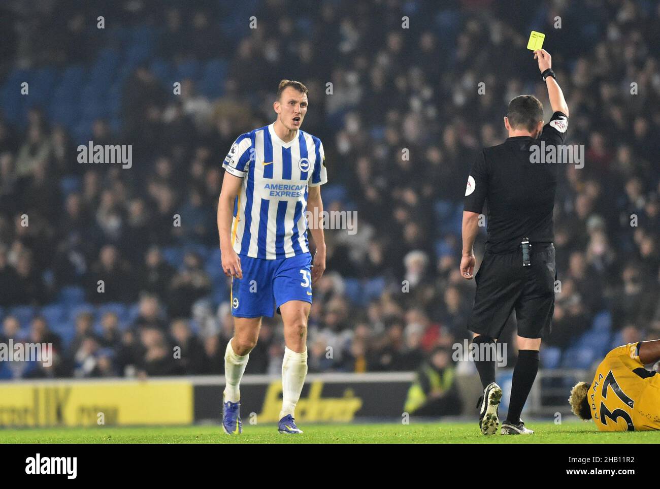 Dan Burn of Brighton is shown a yellow card during the Premier League match between Brighton and Hove Albion and Wolverhampton Wanderers  at The American Express Community Stadium  , Brighton,  UK - 15th December 2021- Editorial use only. No merchandising. For Football images FA and Premier League restrictions apply inc. no internet/mobile usage without FAPL license - for details contact Football Dataco Stock Photo