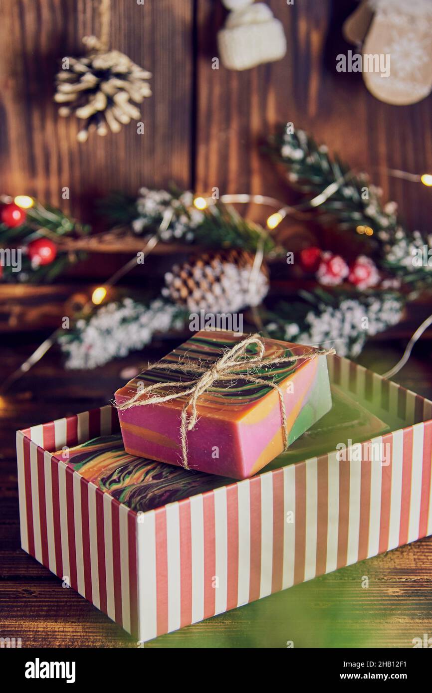 Bright multicolored handmade soap in a gift box on the background of a New Year's decor. Stock Photo