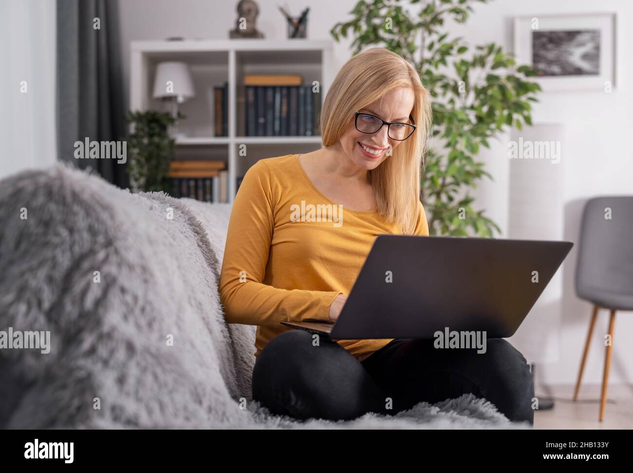 Woman sitting on sofa with laptop Stock Photo