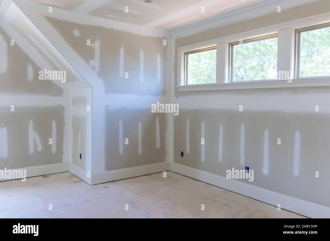 Finishing plastering drywall in ready for paint with new house Stock