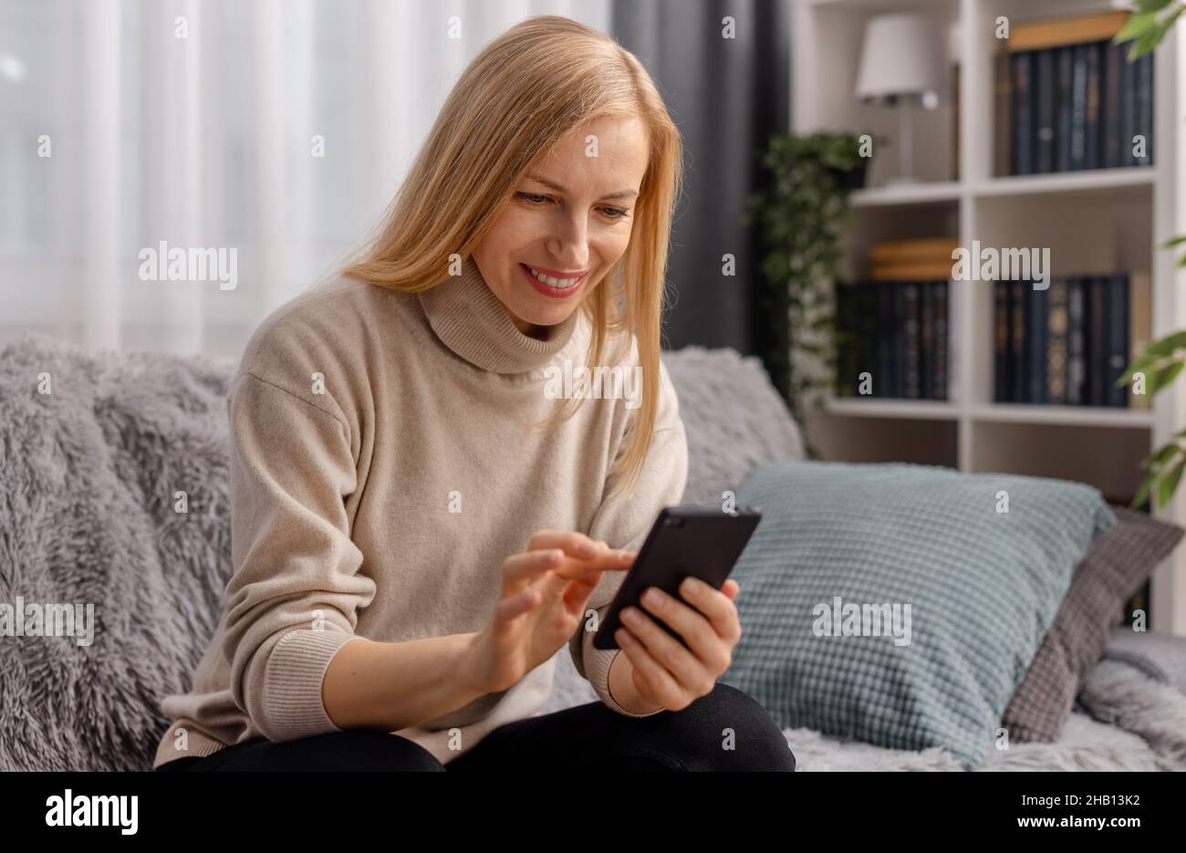 Woman using cell phone at home Stock Photo