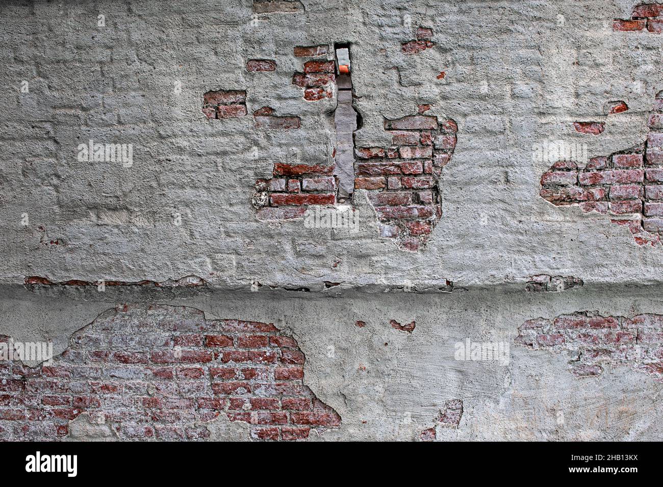old brick wall with peeling white paint and small window Stock Photo