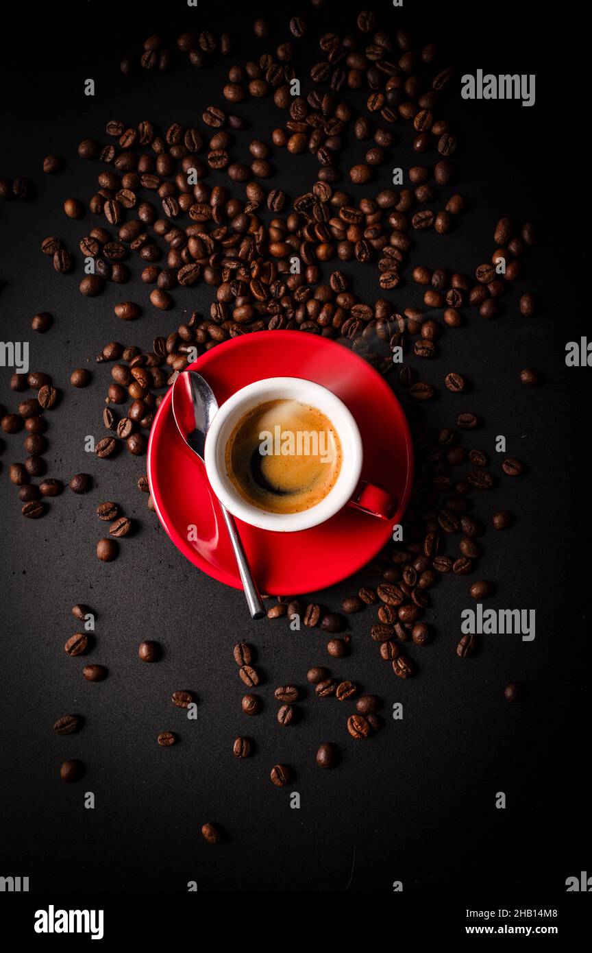 Vertical shot of  a cup of coffee with roasted beans on a dark surface Stock Photo