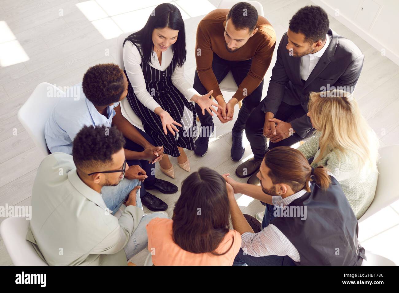 Diverse people sit in circle engaged in teambuilding activity Stock Photo
