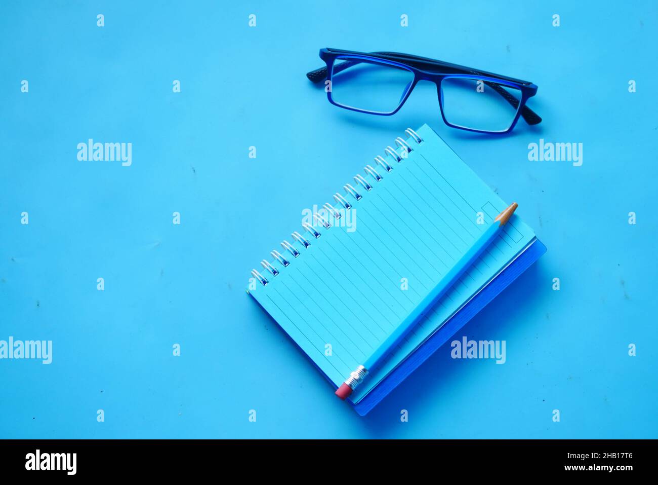 high angle view of blue color notepad with pencil on blue desk  Stock Photo