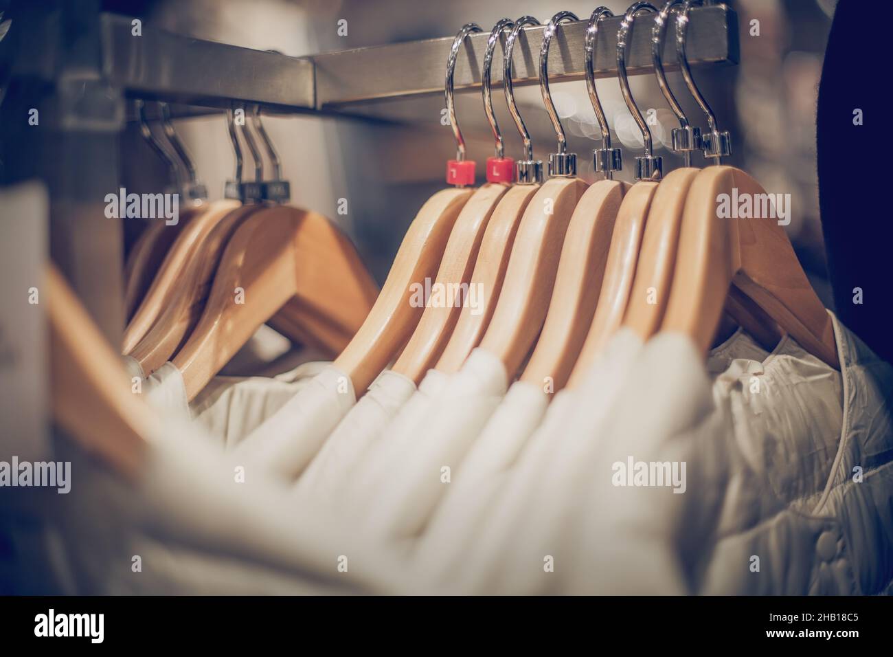 Hangers with clothes on the rail in the store. Shopping in store. Clothes on hangers in shop for sale. Blur background. Fashionable clothes in a bouti Stock Photo