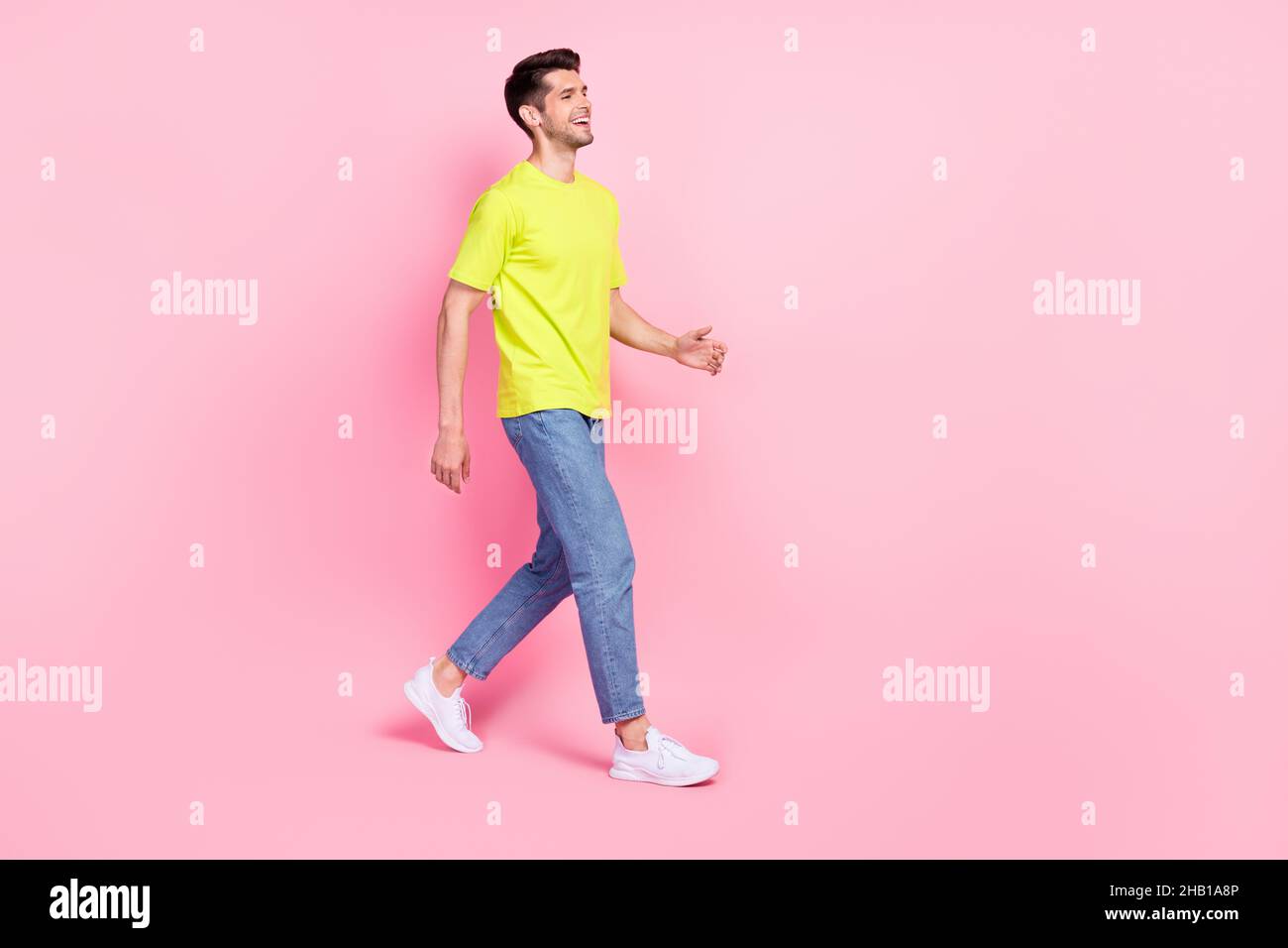Full length body size photo man smiling in stylish outfit walking forward looking copyspace isolated pastel pink color background Stock Photo