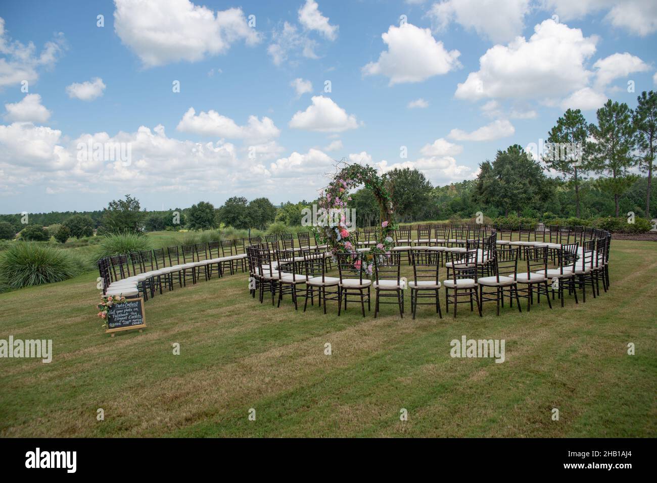 Unique round spiral chair pattern wedding ceremony setting at rolling hills countryside with brown chiavari chairs and white cushions Stock Photo
