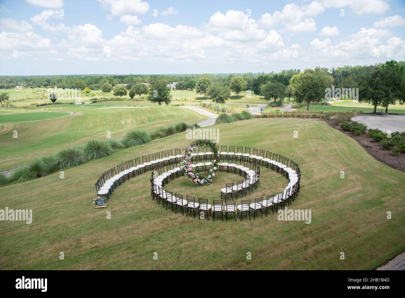 Unique round spiral chair pattern wedding ceremony setting at rolling hills countryside with brown chiavari chairs and white cushions Stock Photo