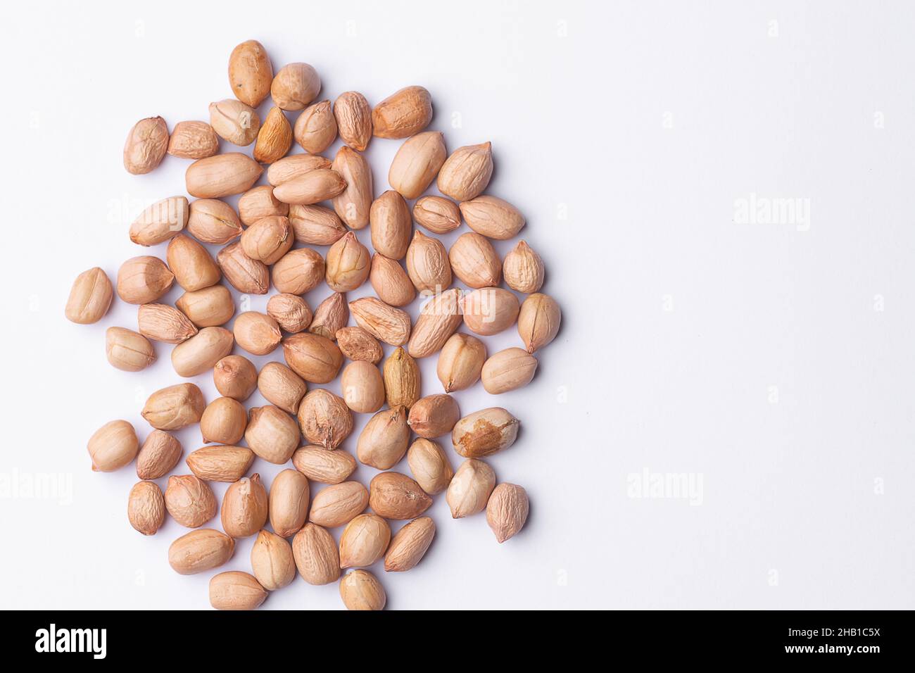 Peanuts also known as groundnut which are edible seeds spread on the white background. Used selective focus. Stock Photo