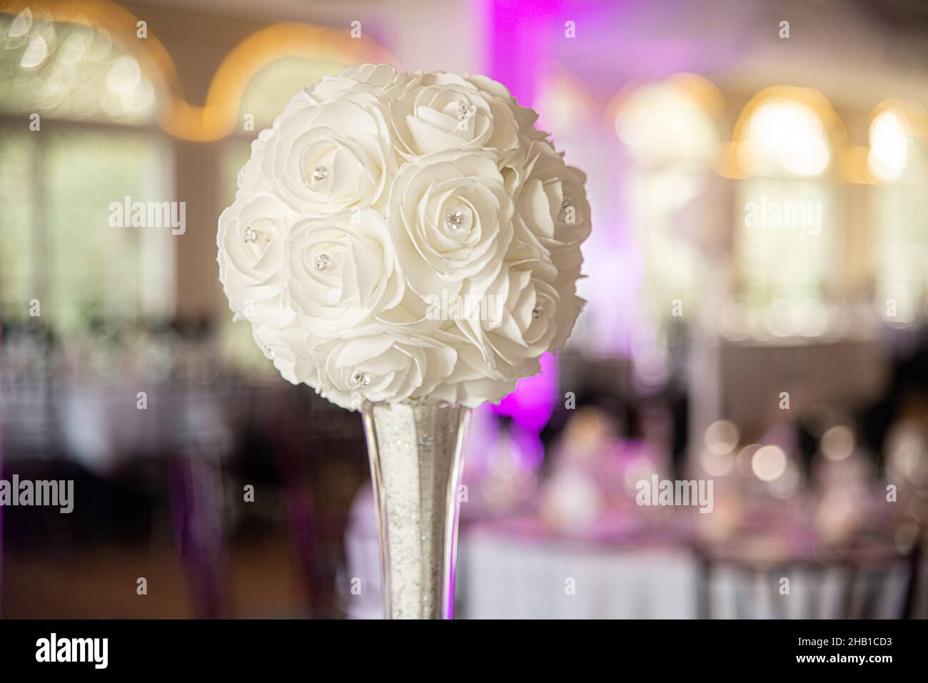 Artificial white flower balls with diamonds in glass vase at wedding