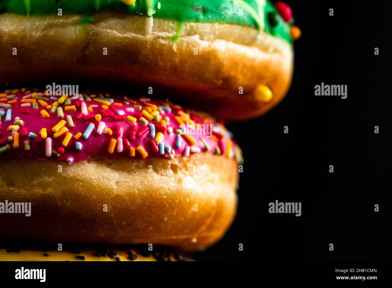 Glazed donuts with sprinkles isolated on a black surface Stock Photo