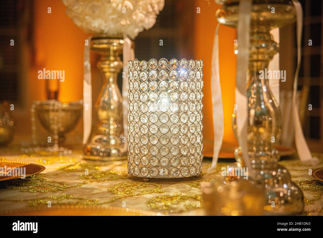 Glass candle holder centerpiece between two gold candlesticks on ornate