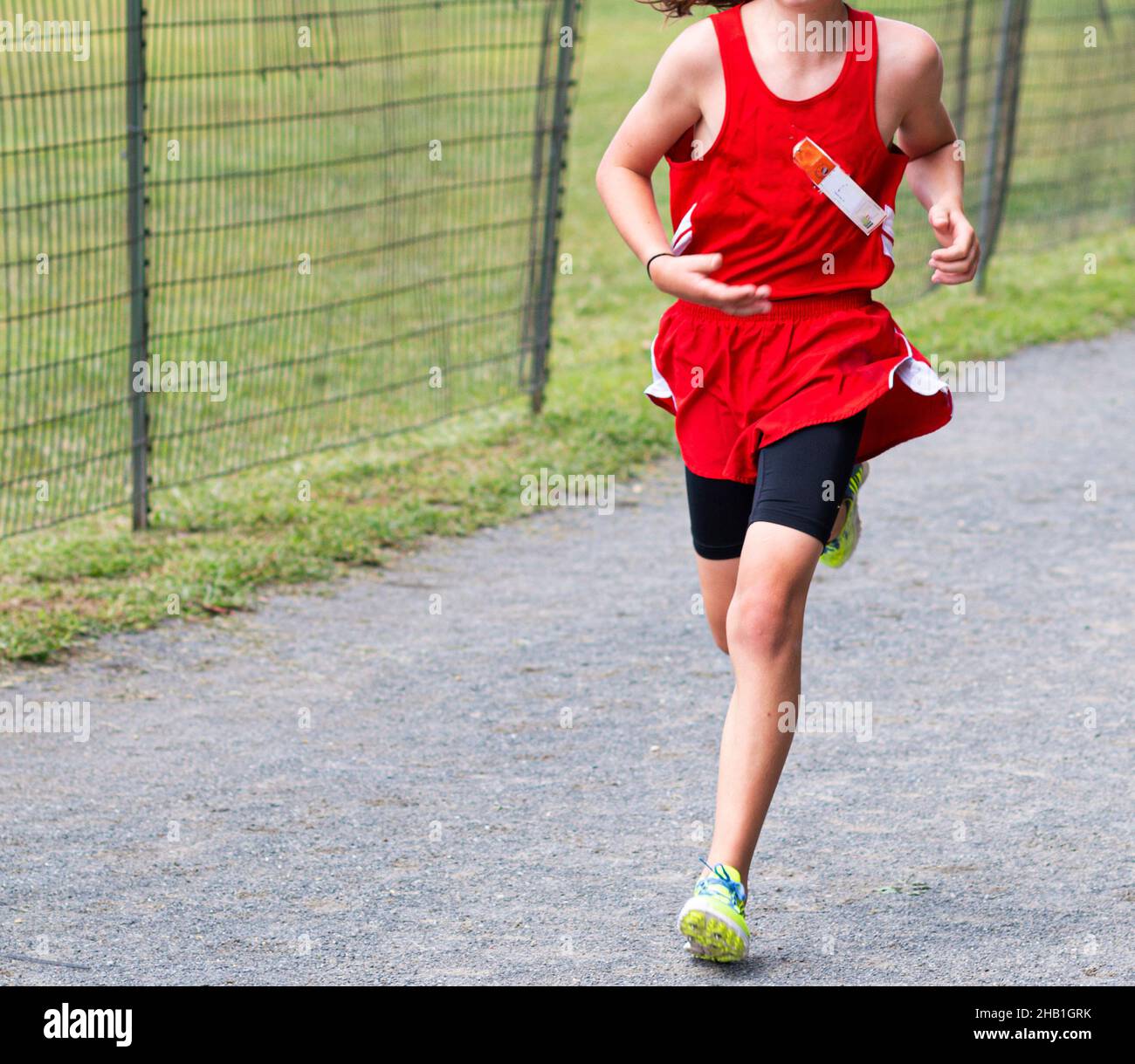 A high school boy is finishing a 5K cross country race on a gravel path in Van Cortlandt park in the Bronx. Stock Photo