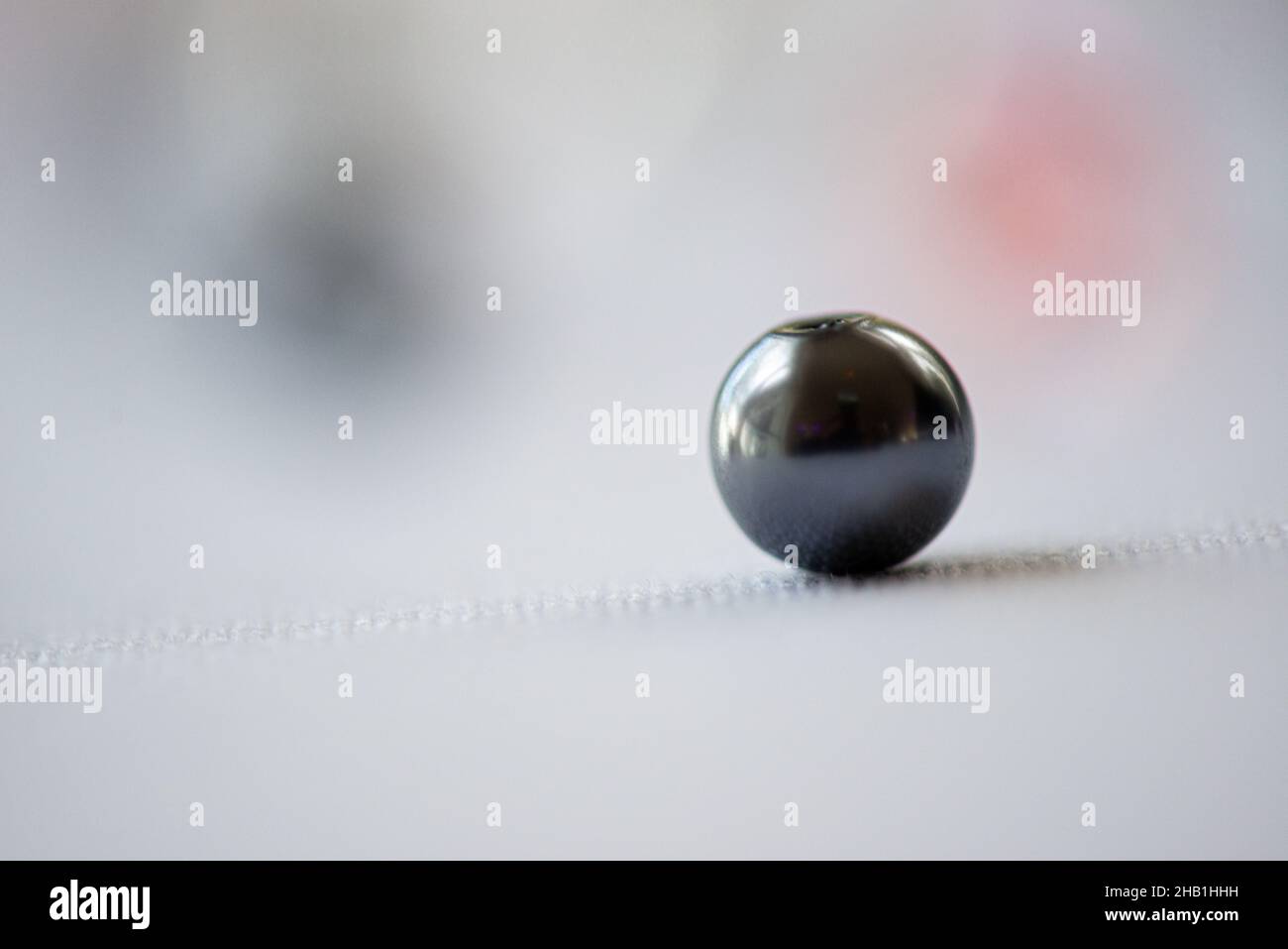 One isolated black marble on white surface color bokeh background Stock Photo