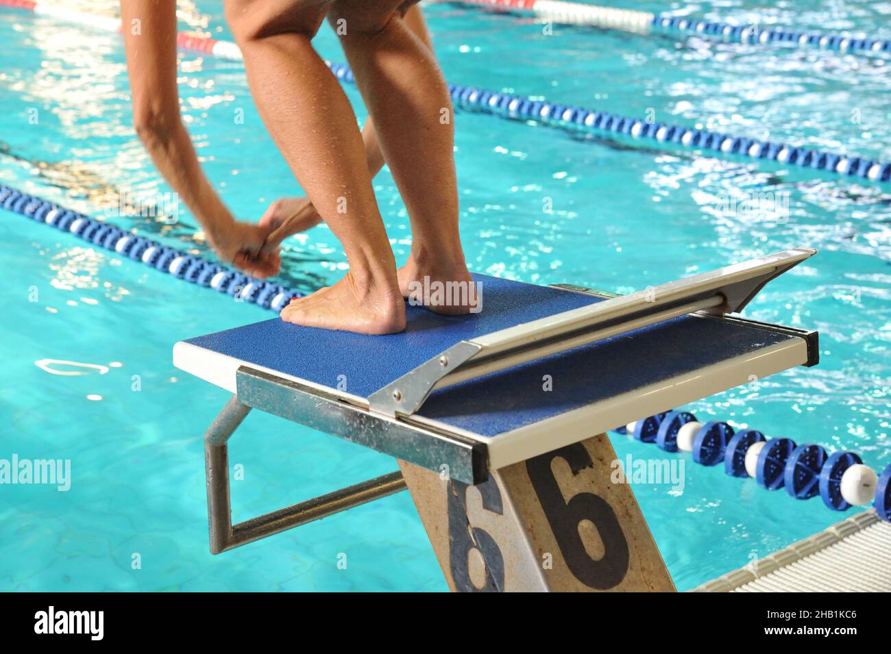 Young female standing on a diving board ready to jump into the swimming