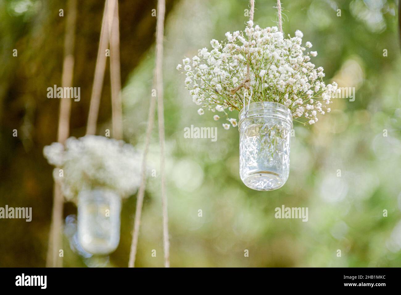 Mason jars filled with babies breathe flowers hanging from trees at