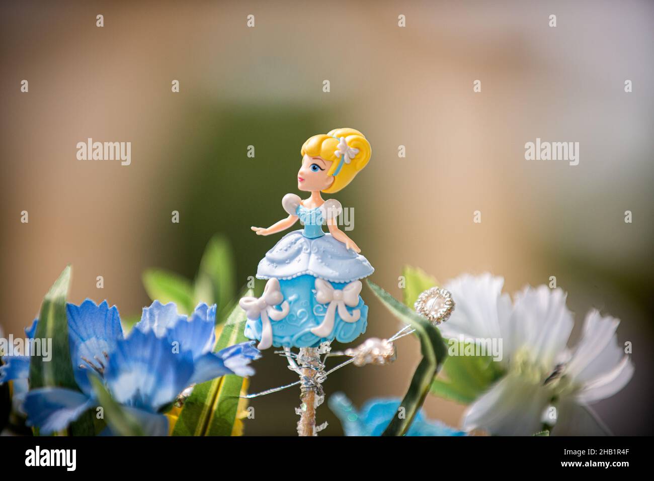Blond Cinderella cake topper wearing blue and white dress surrounded by blue flowers Stock Photo