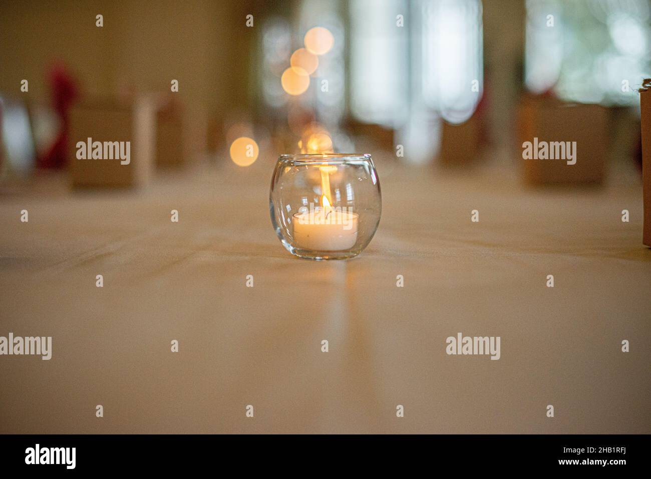 Round glass candle holder with lit candle on luxury dinner table
