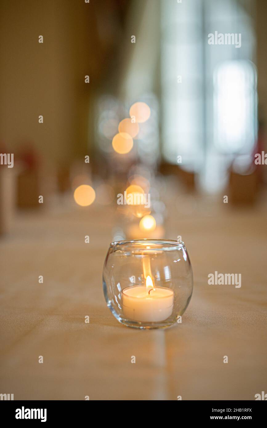 Round glass candle holder with lit candle on luxury dinner table