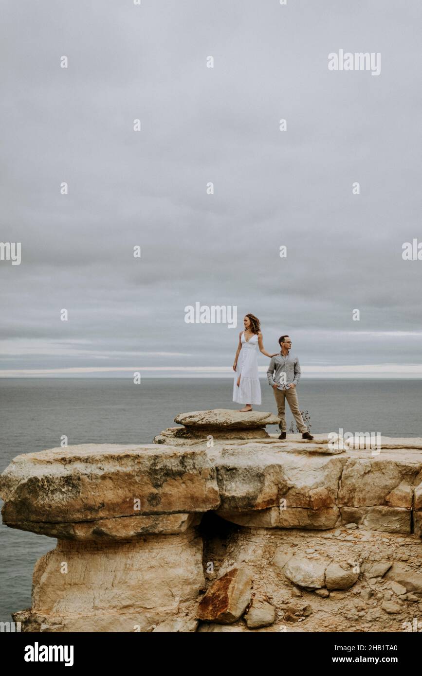 Dressed up couple stand on rock formation, Lake Superior, Michigan. Stock Photo