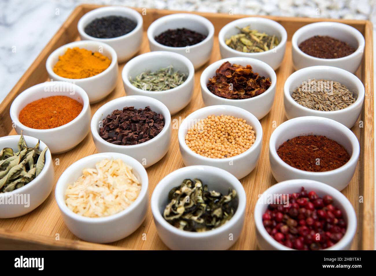 A selection of herbs and spices in small round containers displayed on