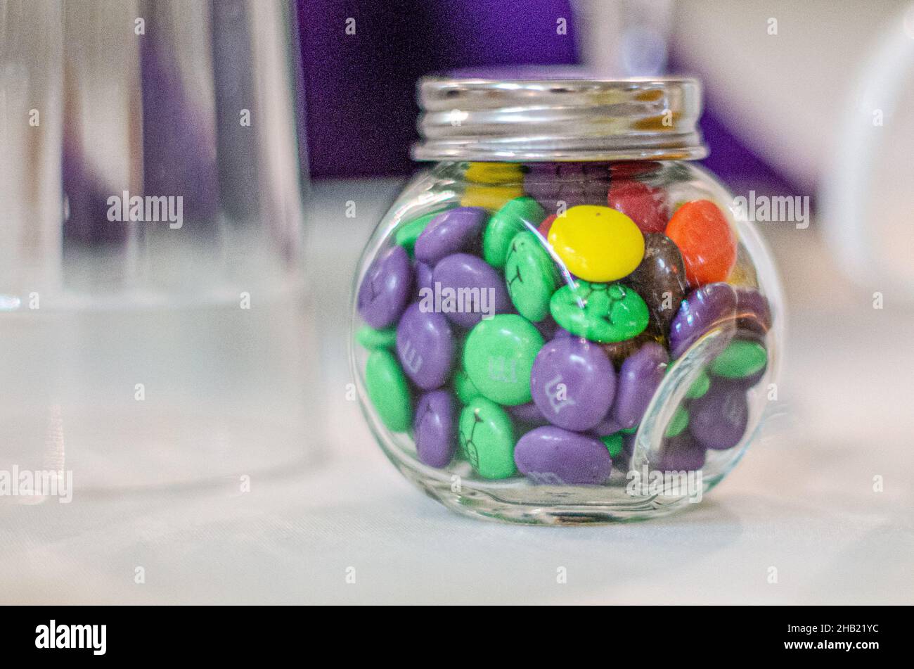 Glass candy jar filled with assorted colored candies at wedding reception dessert bar Stock Photo