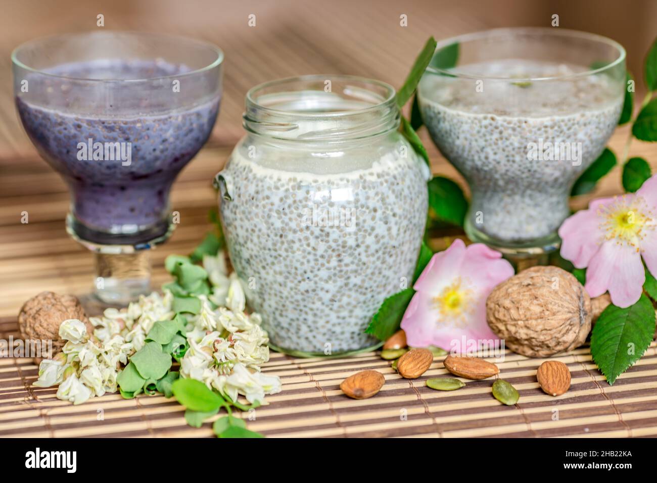 Top view of chia seed pudding with dog-rose flowers, almond milk, and nuts on glass containers Stock Photo