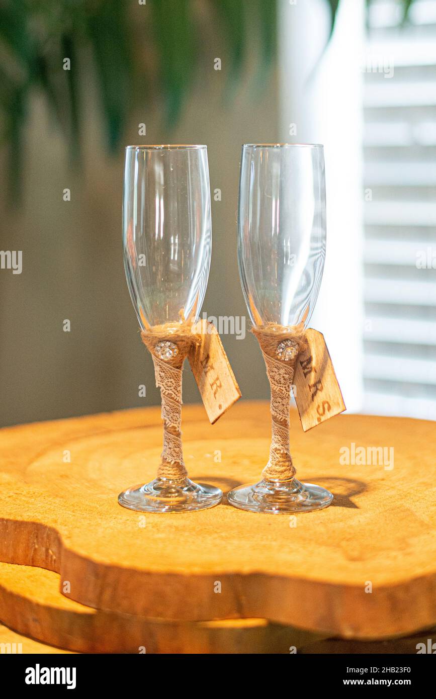 Two empty Bride and groom champagne  glasses wrapped in burlap on wood logs at  wedding reception Stock Photo
