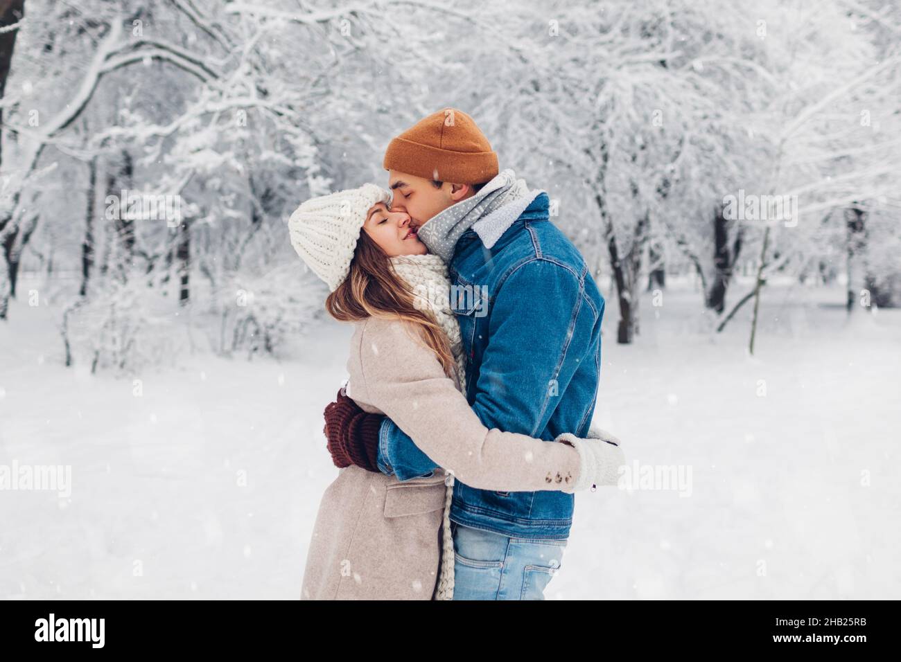 Young stylish loving couple kissing in winter park. Man and woman ...