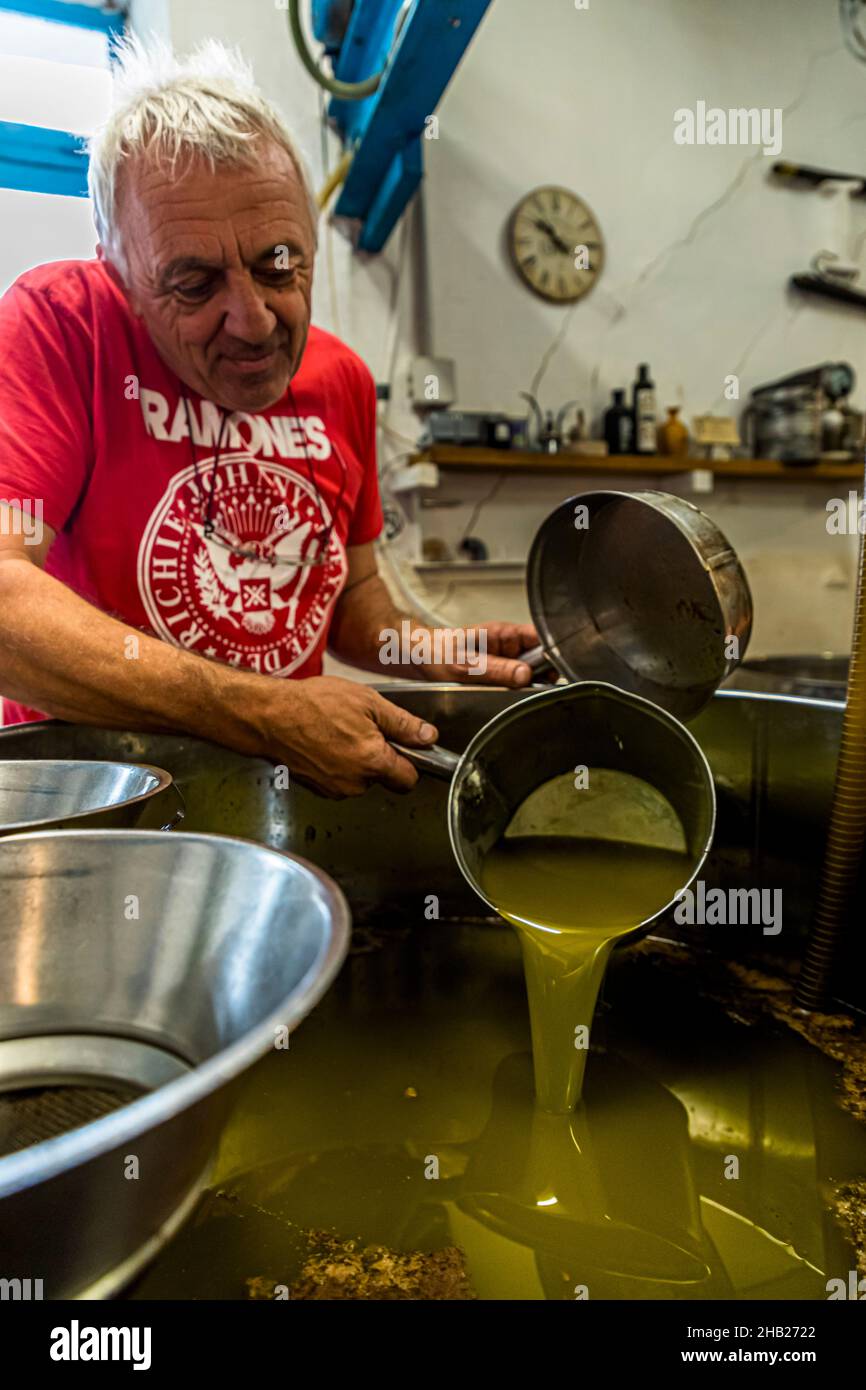 Traditional Oil Mill (Moulin a Huile Traditionnel) in Draguignan, France. After the pressing process, the water-oil mixture stands in open containers. After a good hour, Fabrice Godet begins to skim off the olive oil floating on top. The fruit water sinks to the bottom Stock Photo