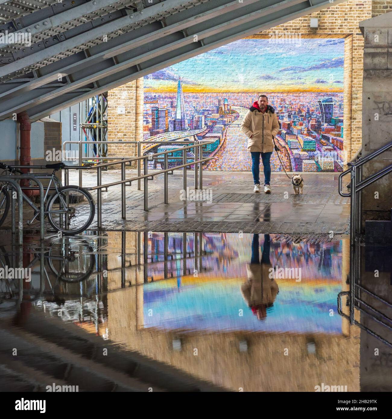 People walking in front of a mural into a flooded underpass beneath