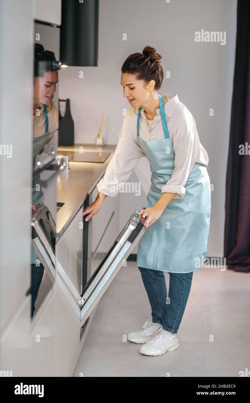 Housewife in apron filling the dishwasher Stock Photo