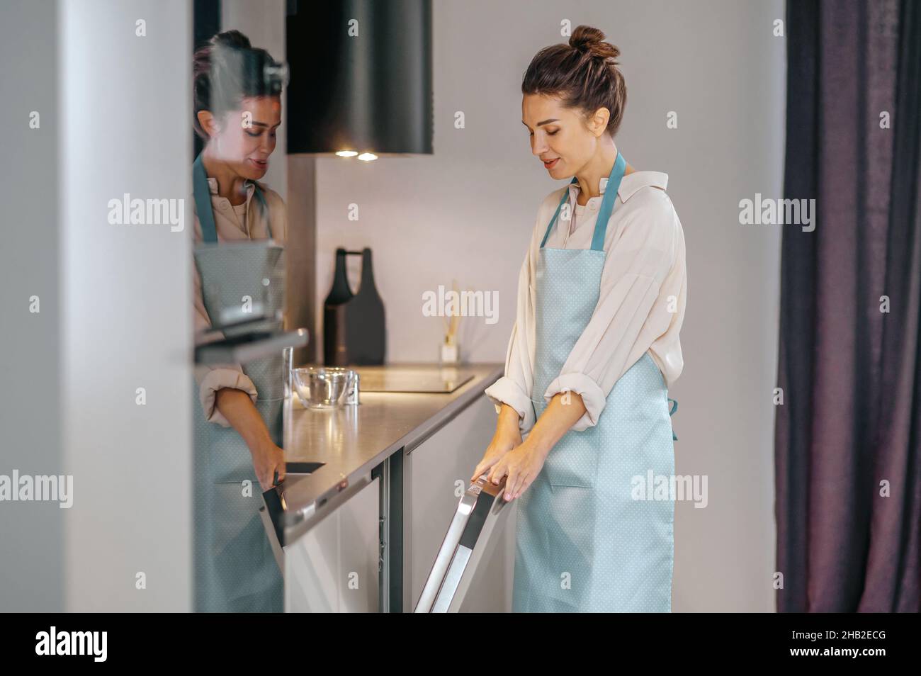 Housewife in apron filling the dishwasher Stock Photo