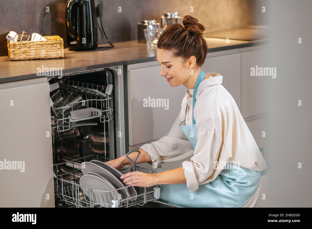 Housewife washing plates in the dishwasher Stock Photo