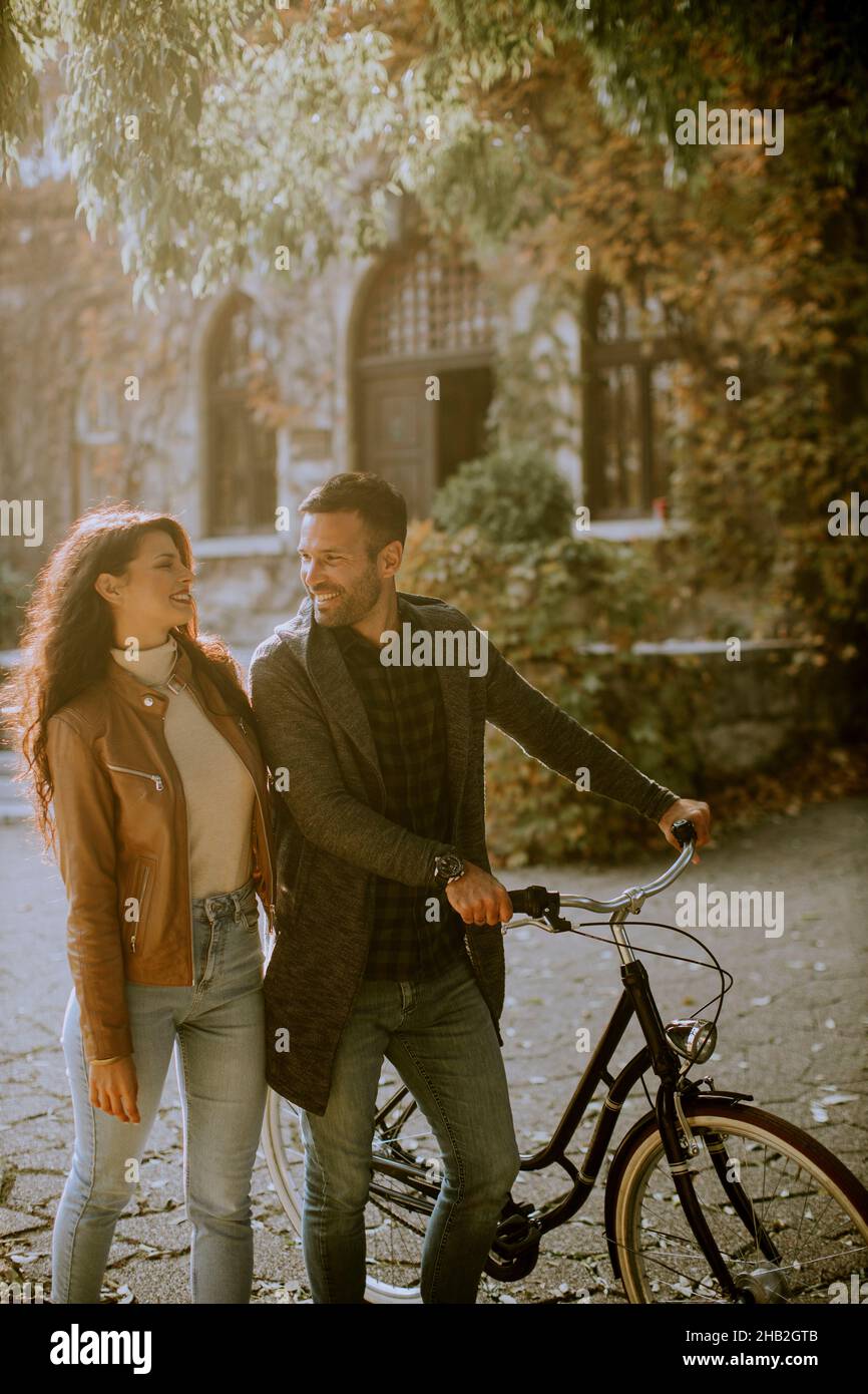 Handsome young couple walking with bicycle in autumn park Stock Photo ...