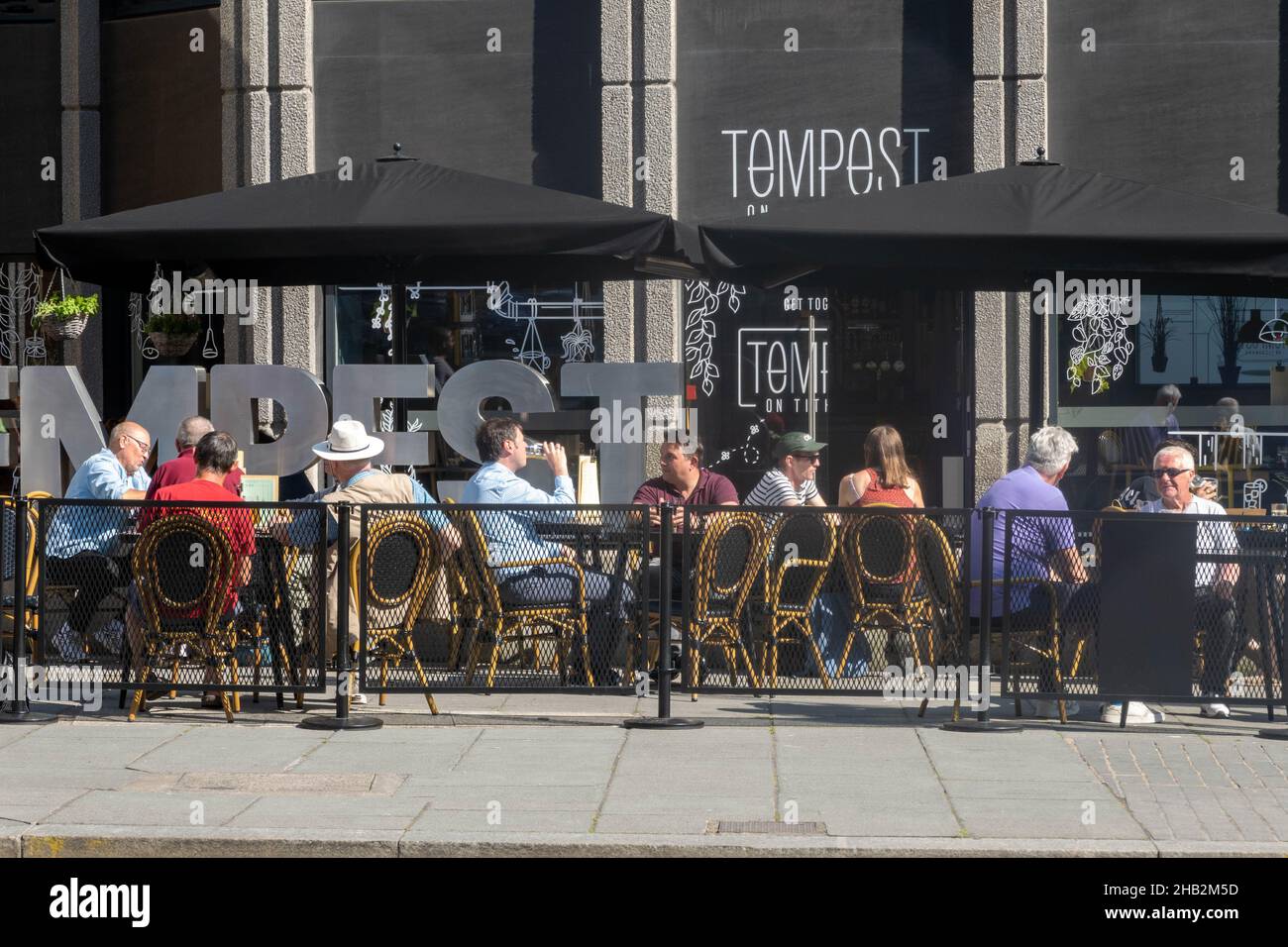 Friends enjoying a drink in the summer sunshine outside the Tempest bar restaurant Stock Photo