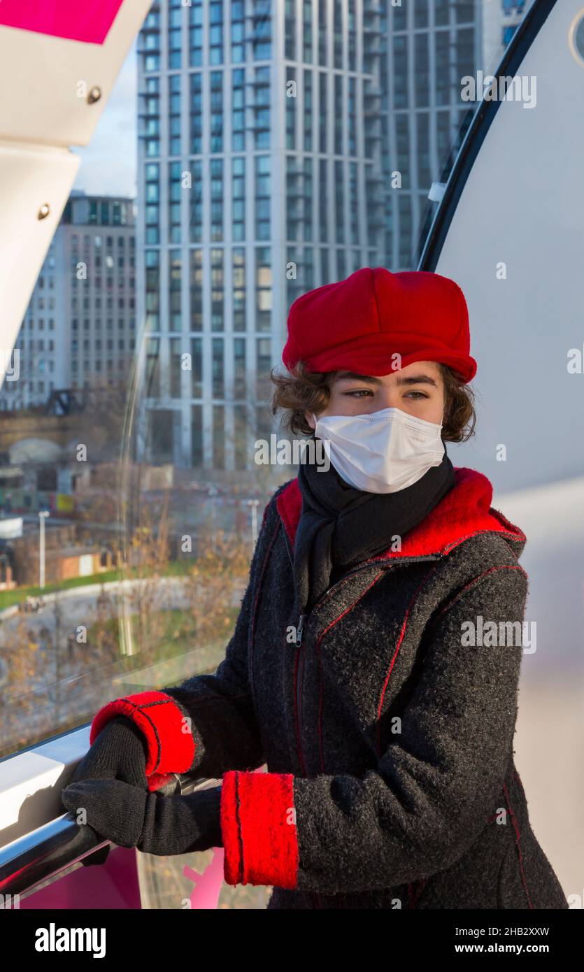 Young woman wearing face mask during Covid-19 Coronavirus pandemic posing for photo in London Eye pod, Southbank, London UK in December Stock Photo