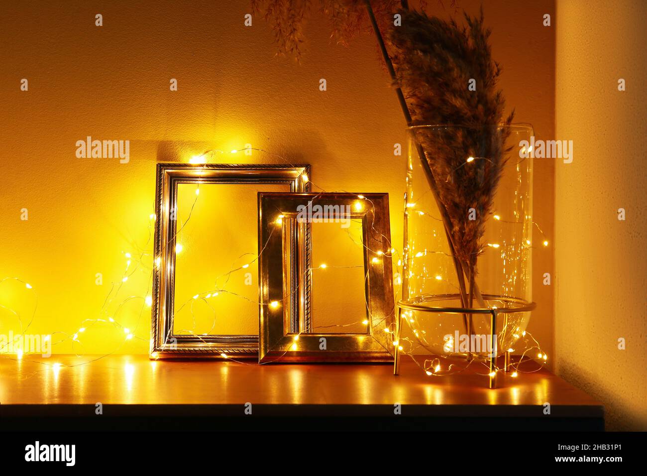 Photo frames, vase with reed flowers and Christmas lights on table in dark  room Stock Photo - Alamy