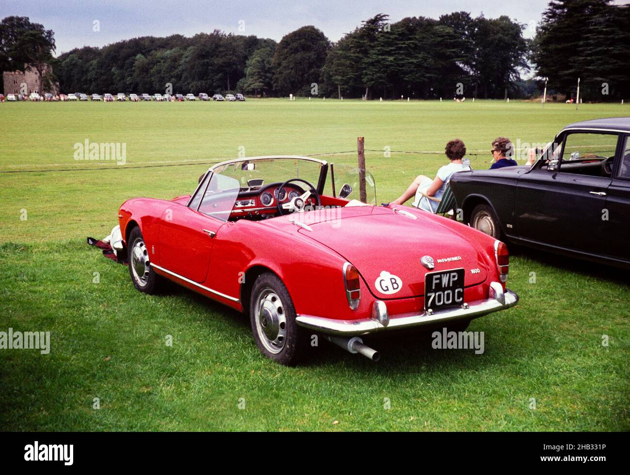 Red Alfa-Romeo Spider 1600 car at a polo match Cirencester, Gloucestershire, England, UK c 1967 Stock Photo