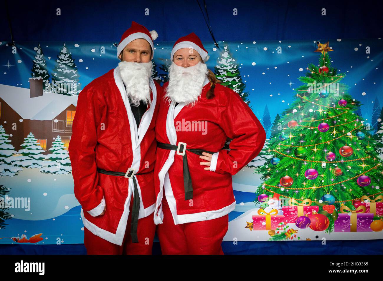 A couple pose in front of a snow scene backdrop before a Santa Dash Stock Photo