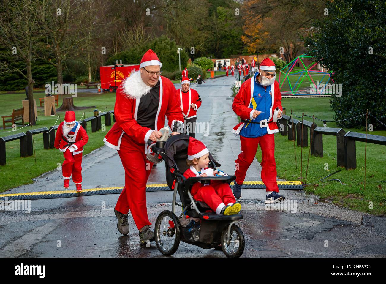 Man with child in a buggy rounds a bend with other santas in The Santa Dash for Warrington Disability Partnership Stock Photo