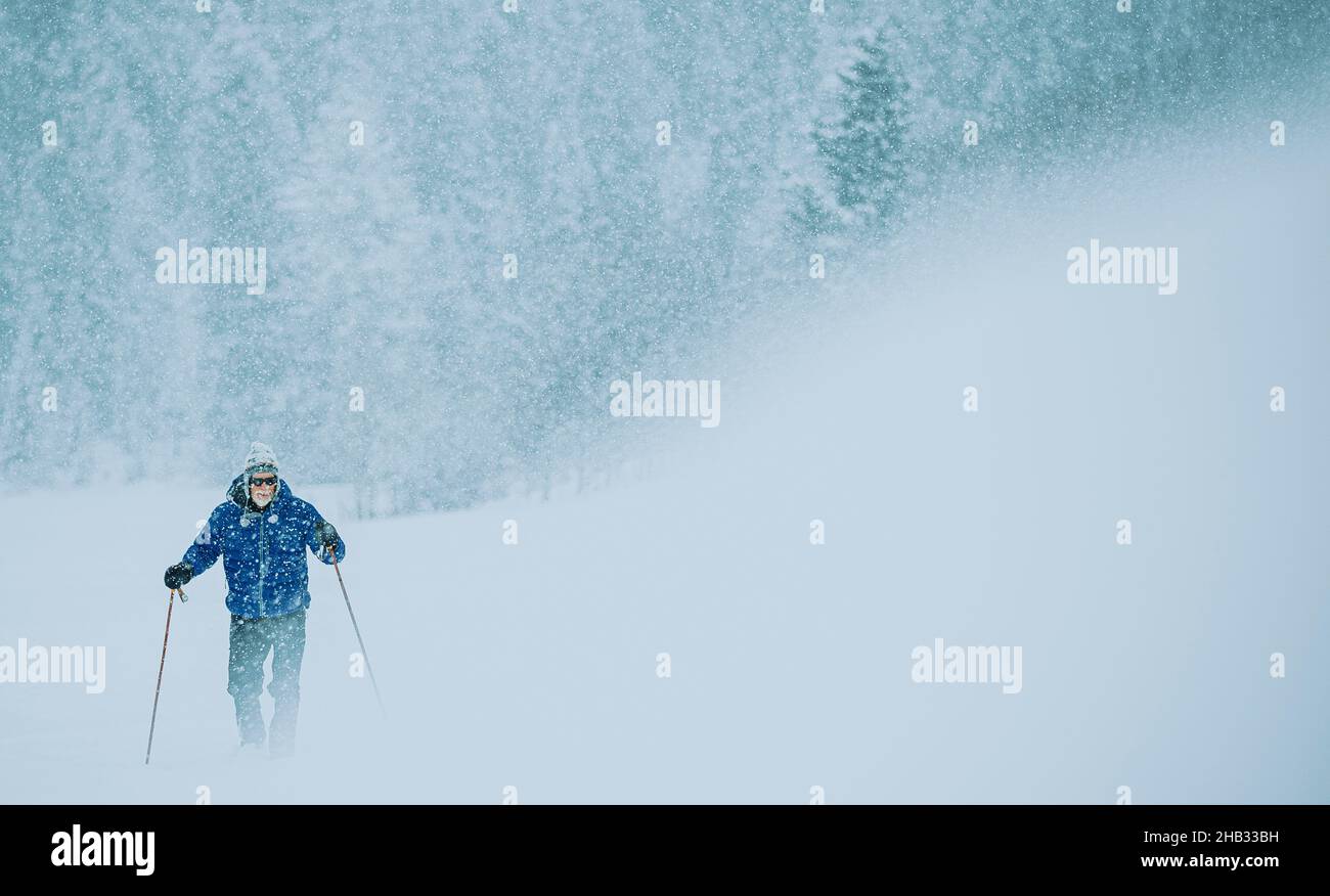 Elderly Man Cross Country Skiing in Snowy conditions Stock Photo
