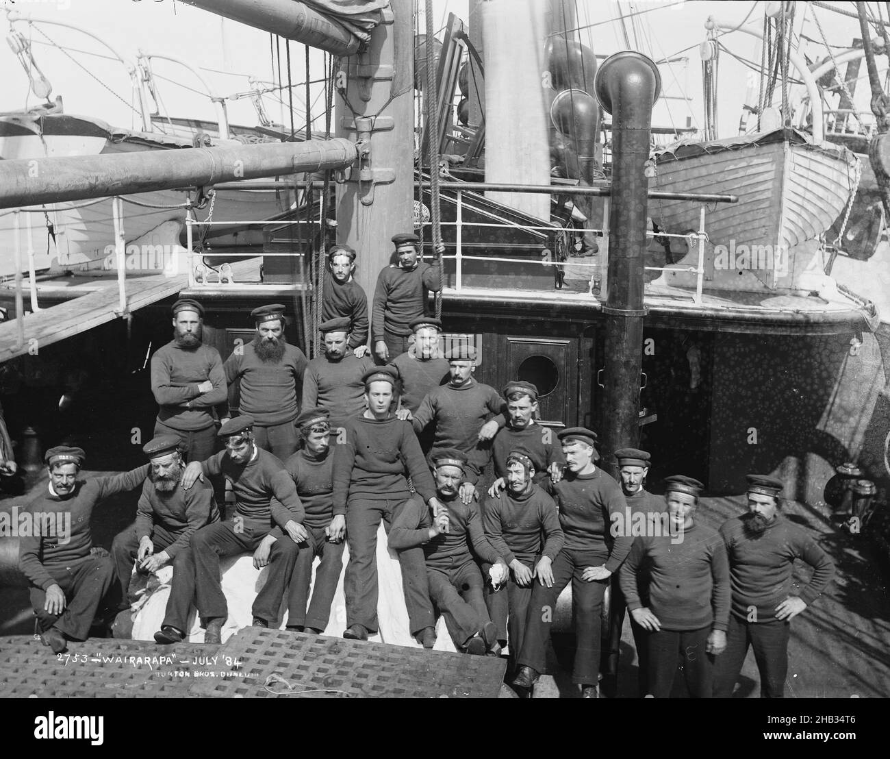 Wairarapa - July '84, Burton Brothers studio, photography studio, 1884, New Zealand, black-and-white photography, Crew of large ship on bottom deck. Nineteen men in Union Steamship Company uniform. Funnel and hight deck behind, with longboats on either side Stock Photo