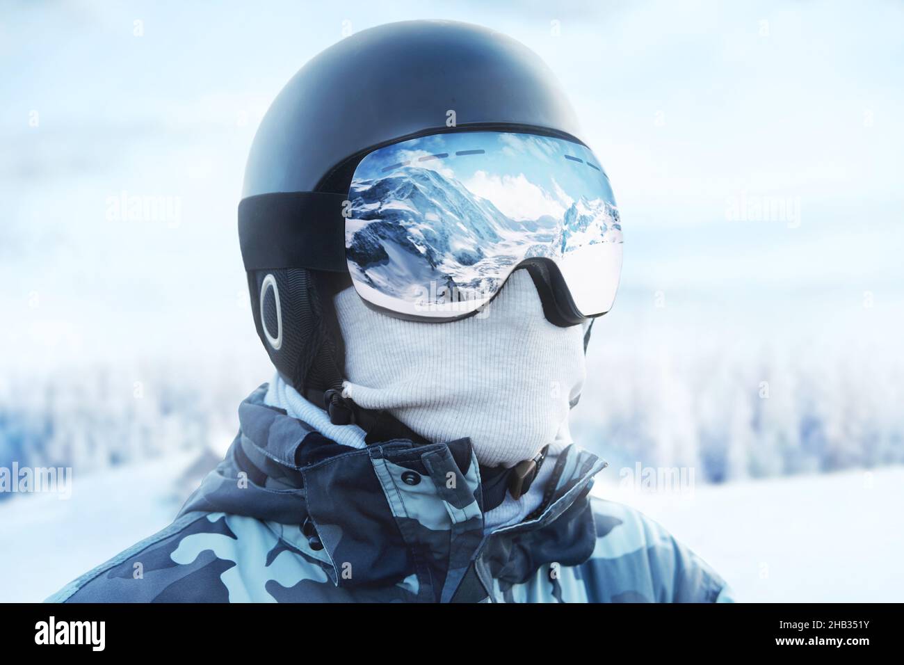 Close up of the ski goggles of a man with the reflection of snowed mountains. Man on the background blue sky. Wearing ski glasses. Winter Sports. Stock Photo