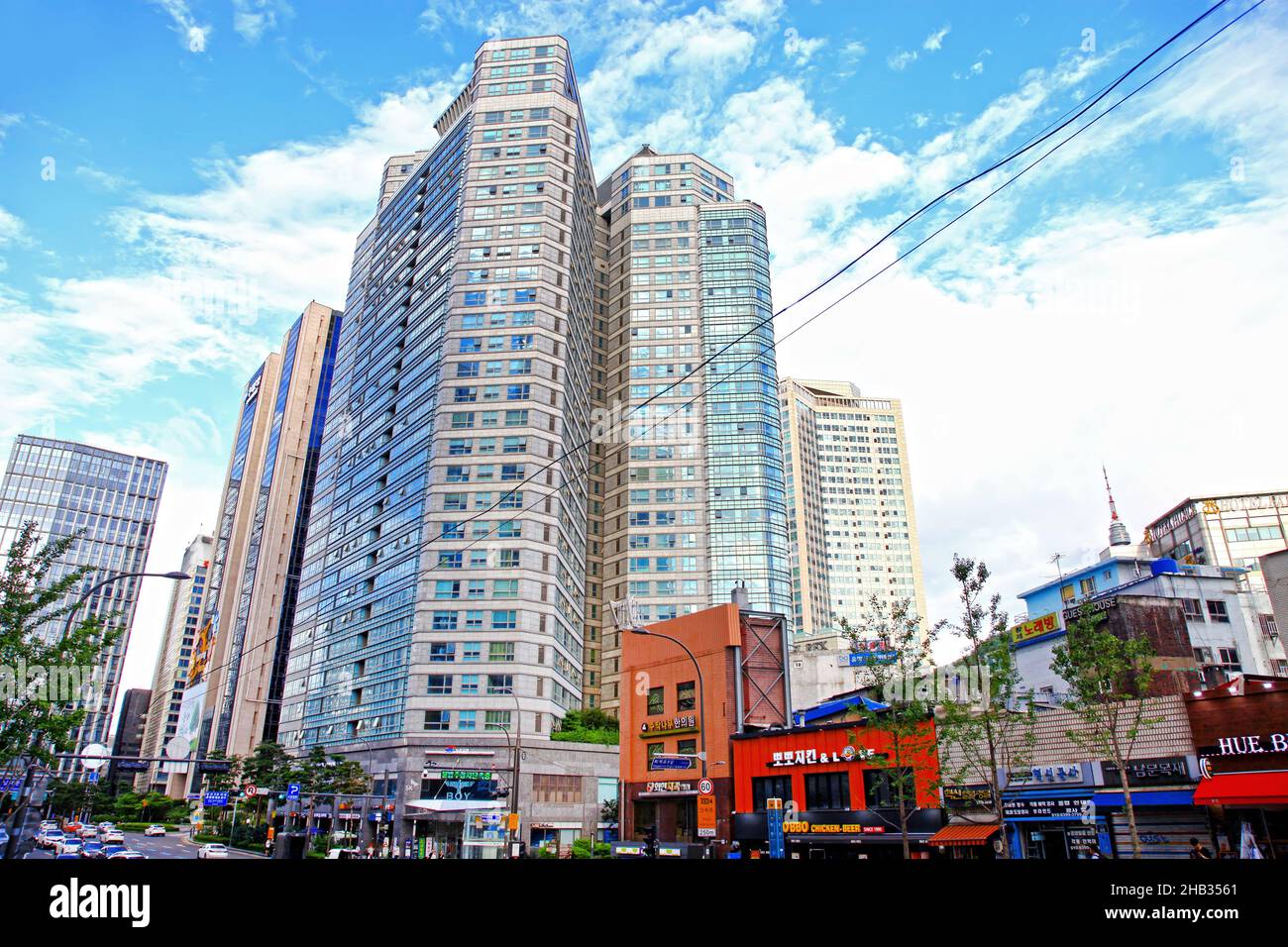 Tall buildings in downtown Seoul in South Korea with a road and several stores in the foreground. Stock Photo