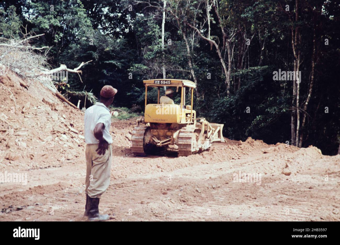 Caterpillar bulldozer repairing the road through rainforest blocked by landslide to Blanchisseuse, Trinidad early 1960s Stock Photo