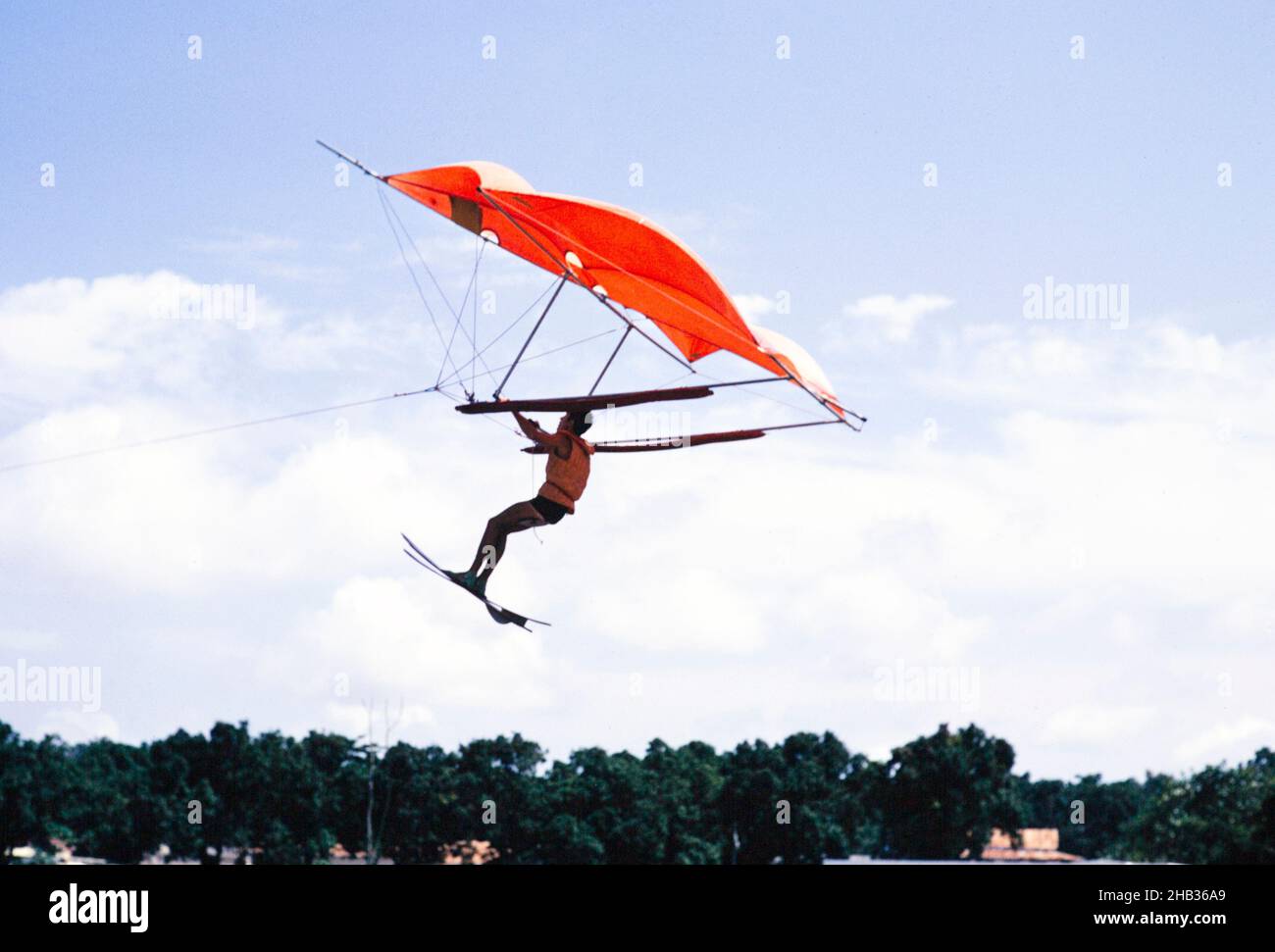 Man flying through the air holding water ski kite, England, Uk 1960s